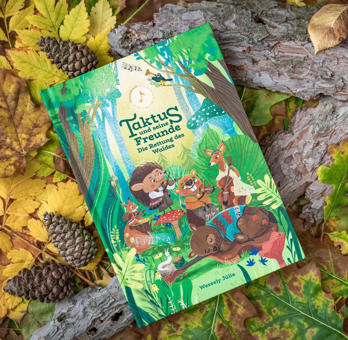 Soundbuch "Taktus und seine Freunde - die Rettung des Waldes" liegt auf Blättern und Rinde